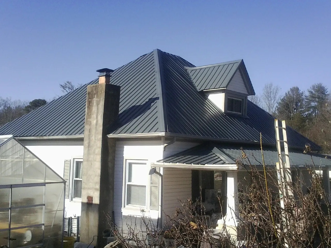 Dark blue standing seam metal roof on a white farmhouse with dormer — Slate & Tile Roof Repair by Roofing Brothers in Shasta