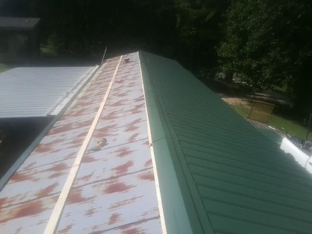 Old rusted panels beside newly installed green metal roofing — Wind Damage Roof Repair by Roofing Brothers in Shasta