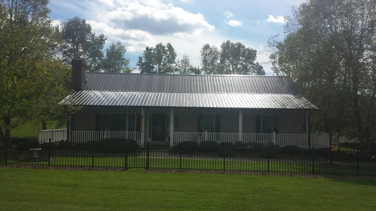 Gray metal roof on a brick ranch with a full width front porch — Gutter Guard Installation work by our crew in Shasta
