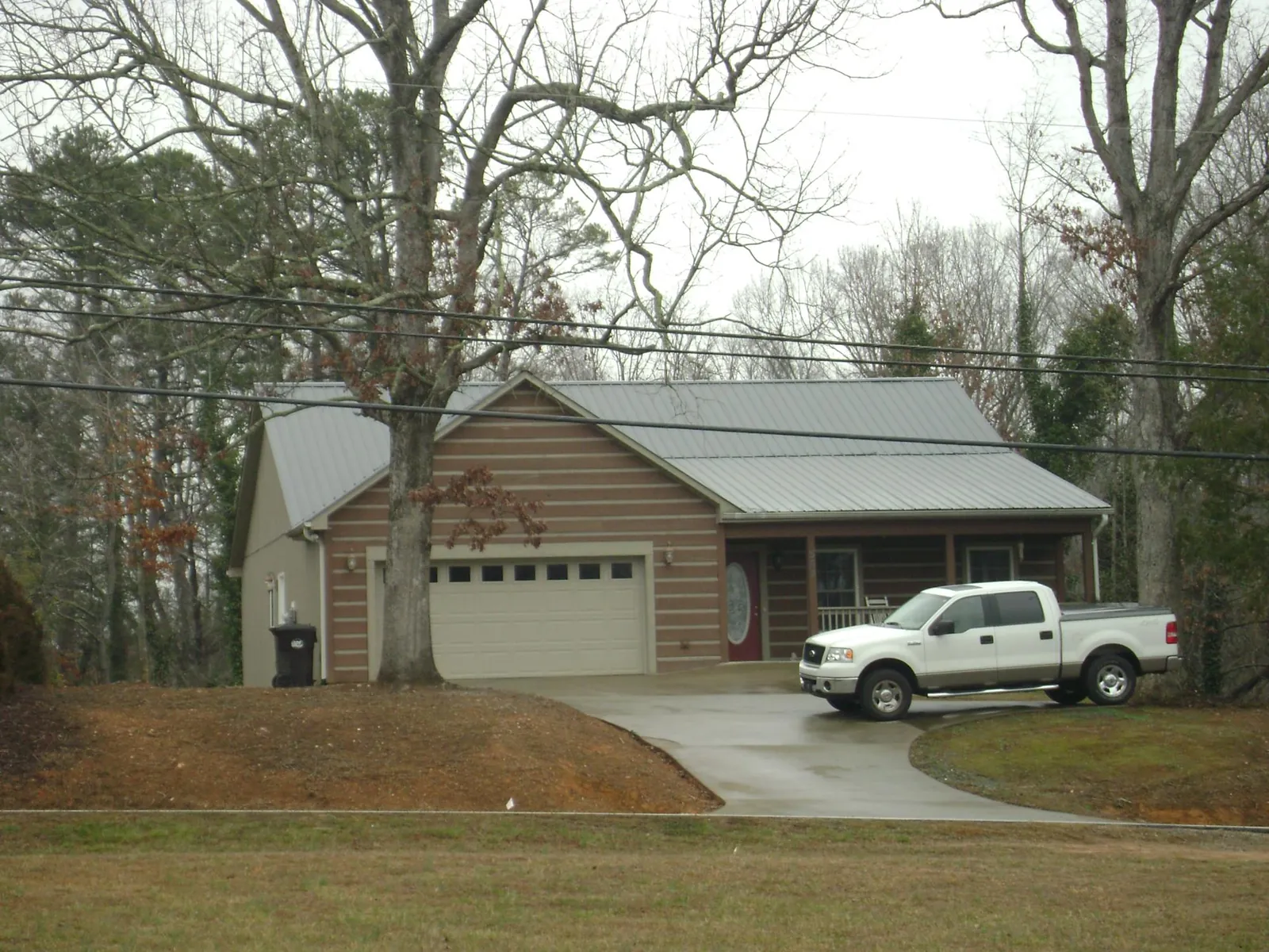Gray metal roof on a log sided house with an attached two car garage in Shasta