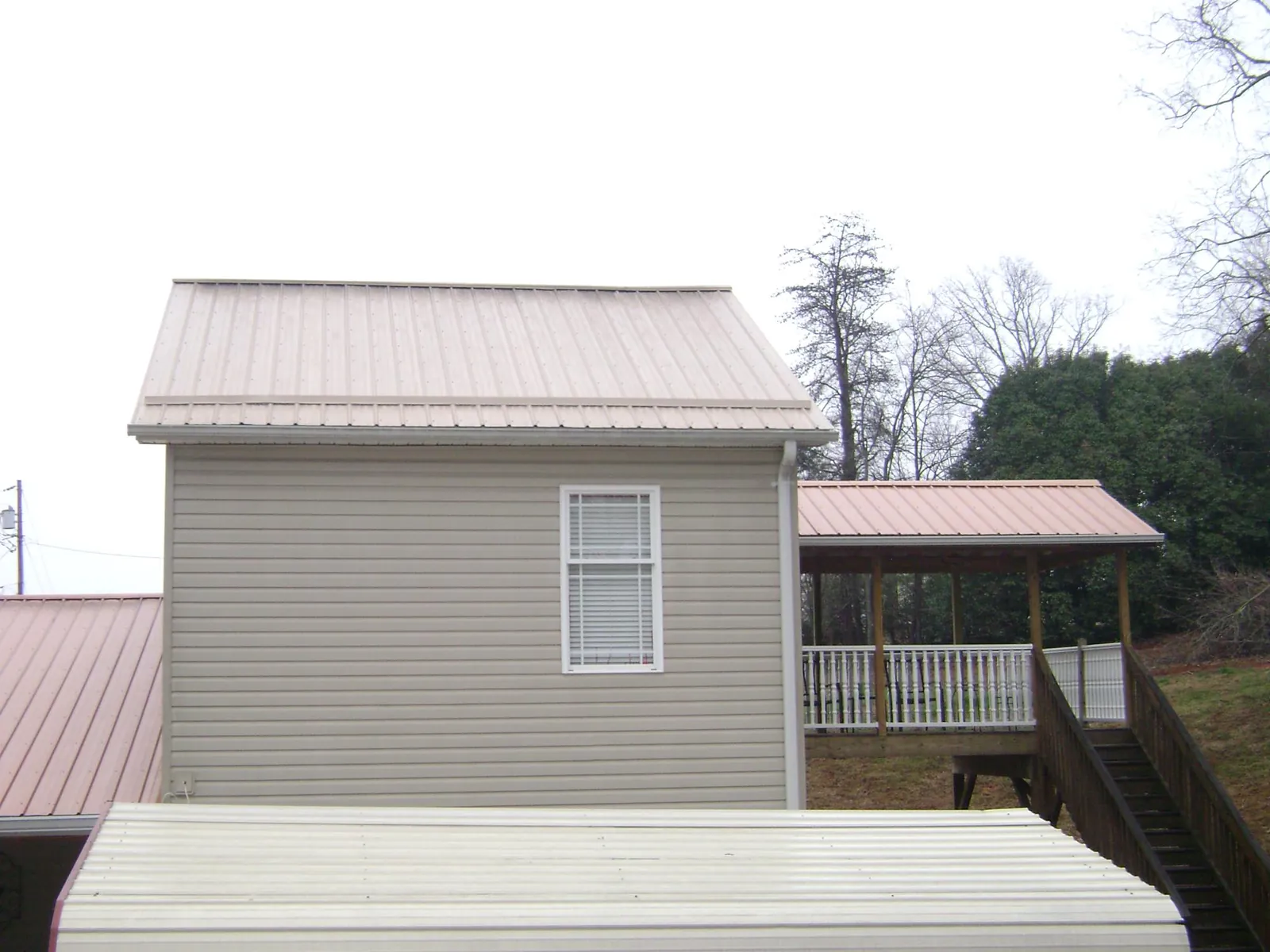 Tan metal roofs on a two story addition and attached porch, from a Roof Replacement job in Shasta