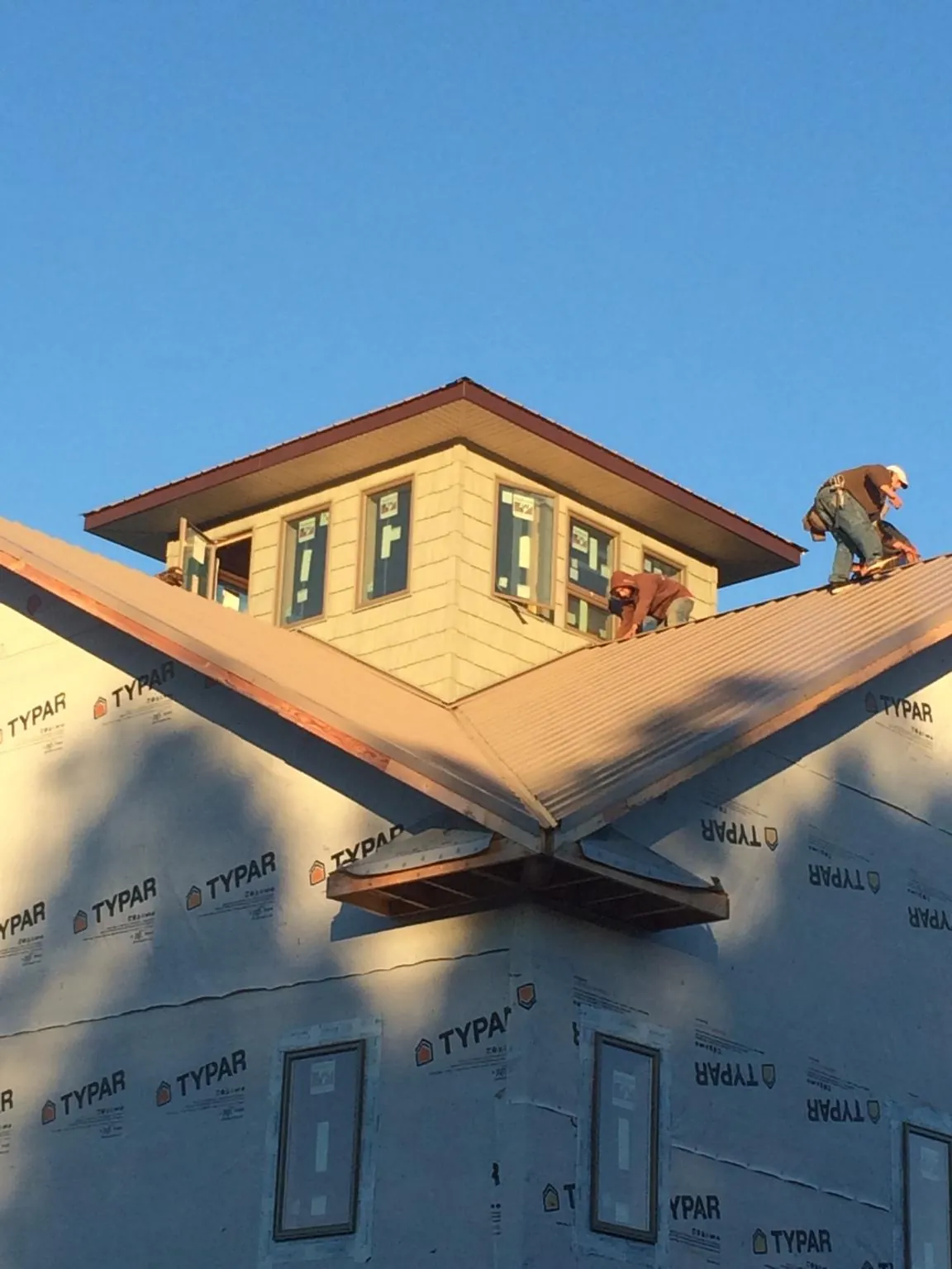 Roofers working around a rooftop cupola on a new metal roof at sunset — Roof Waterproofing in Shasta by Roofing Brothers